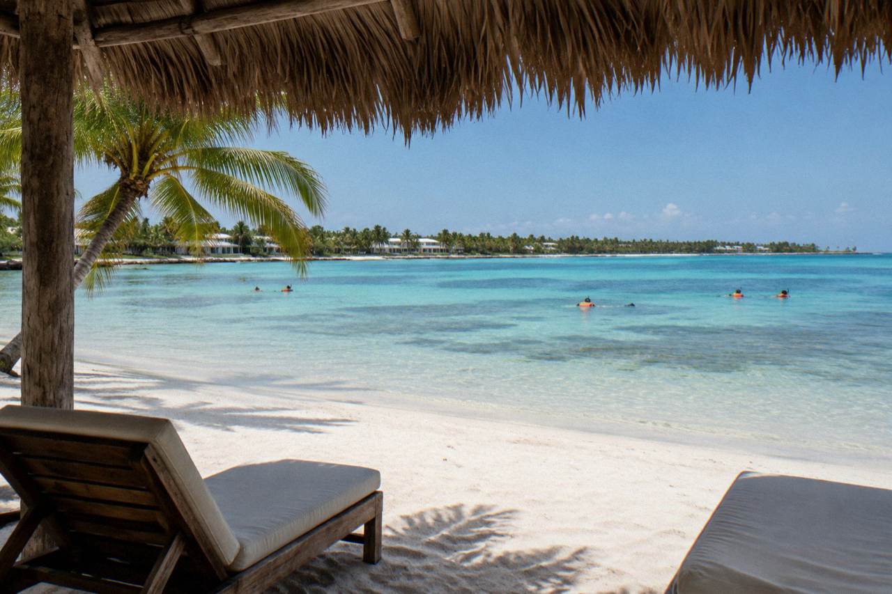 Calm turquoise bay with a sandy beach and palm trees along the shoreline