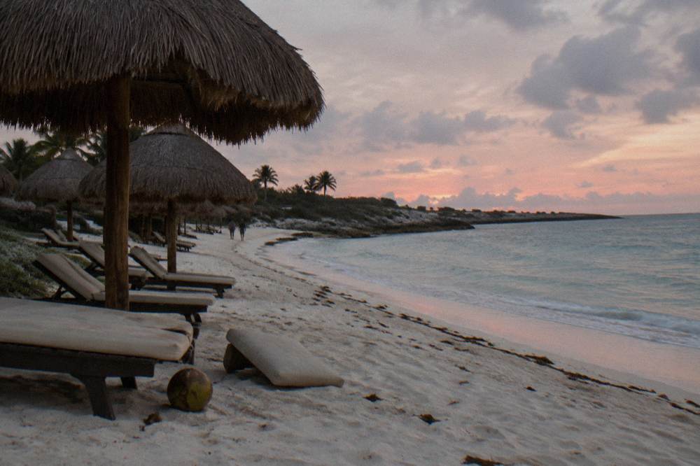 Palapa roofs and lounge chairs on a quiet beach at first light