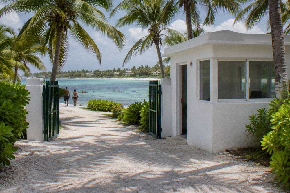 Park entrance walkway with palm trees and a small fee building near the beach