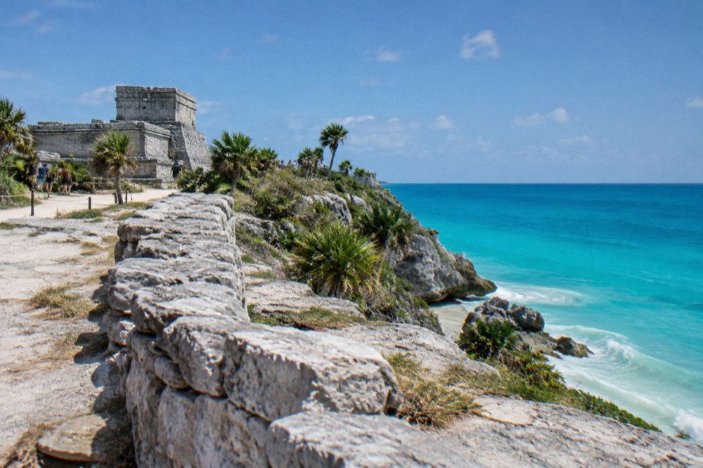 Stone ruin walls overlooking a turquoise sea from a cliff-top archaeological site