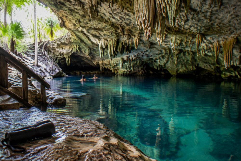 Clear freshwater cenote surrounded by rock walls and jungle vegetation