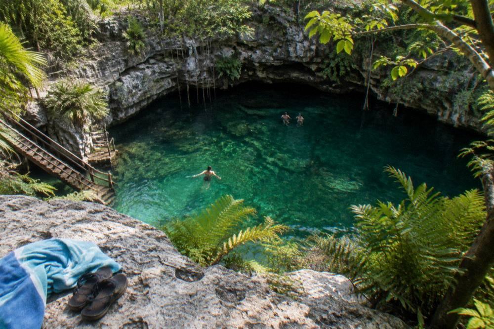 Open freshwater cenote surrounded by limestone rock and jungle vegetation