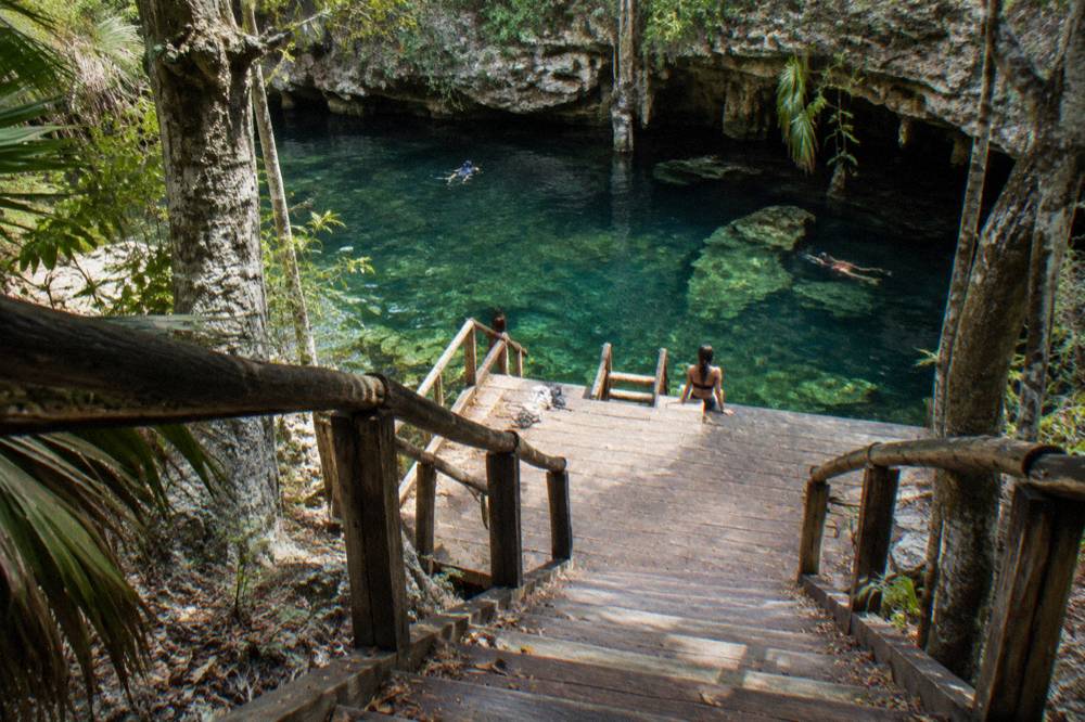 Wooden steps and a platform leading down to clear green water between limestone walls