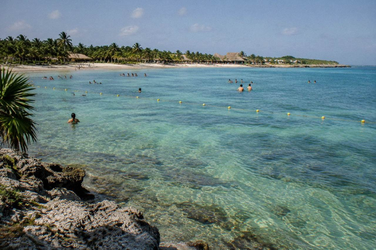 Calm turquoise bay with seagrass beds visible below the surface and a buoy line marking a swimming area