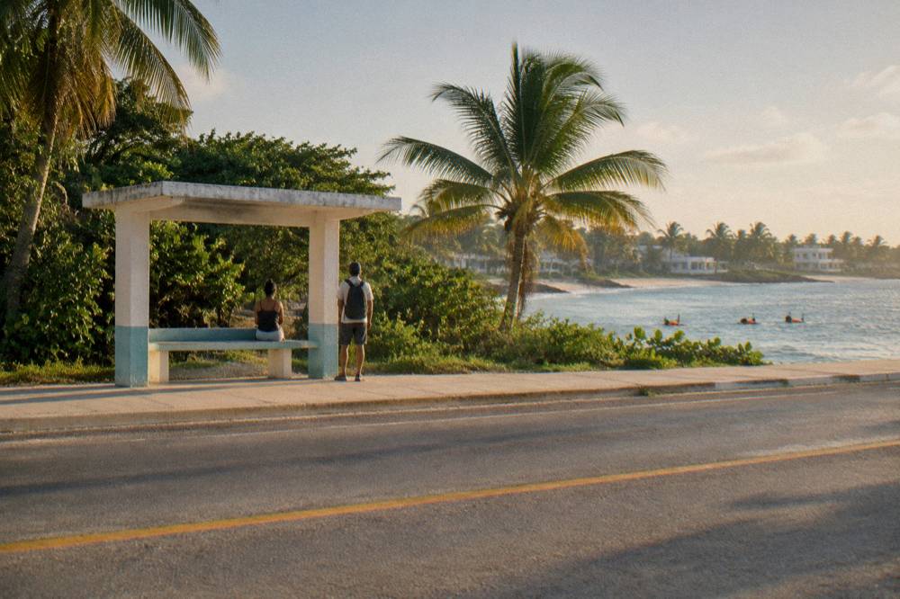 A long straight highway running south beside low jungle and a distant coastline
