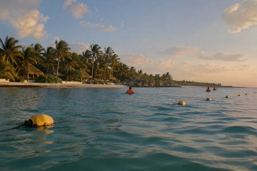 Guided snorkel group in vests swimming near buoy markers in a wide bay